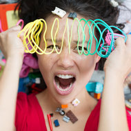 Überforderte Mutter mit Spielzeug rundherum