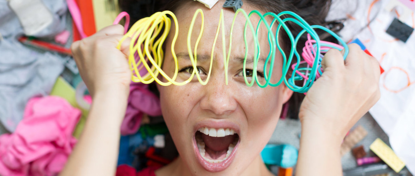 Überforderte Mutter mit Spielzeug rundherum