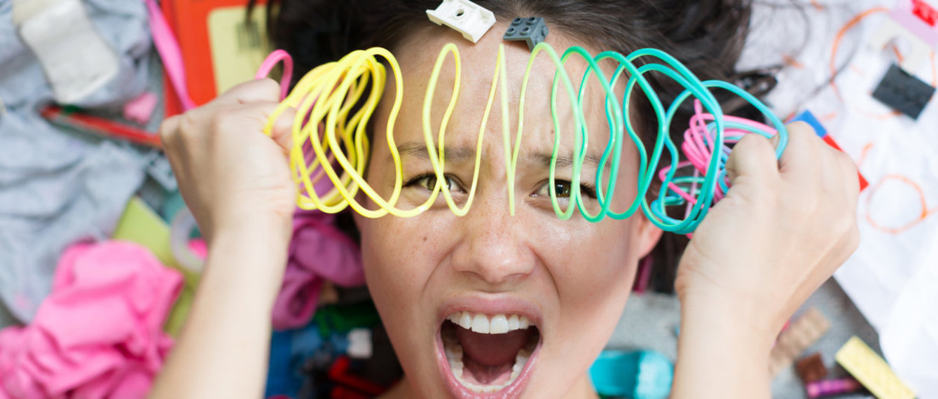 Überforderte Mutter mit Spielzeug rundherum