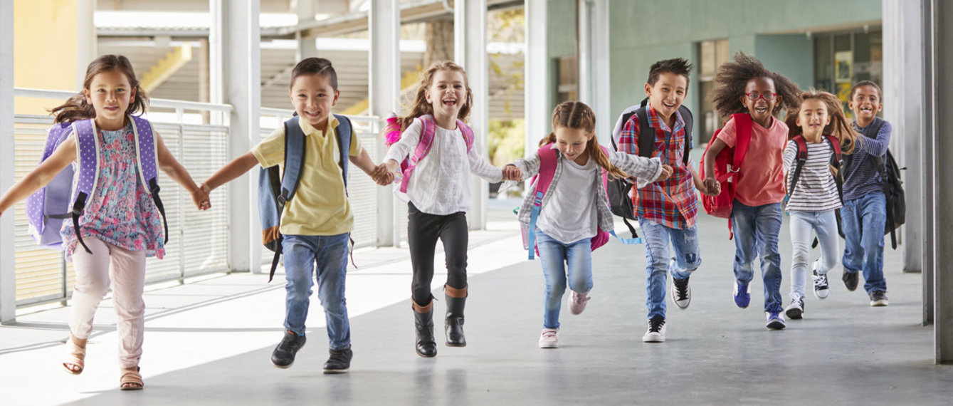 Schüler laufen Hand in Hand am Schulgang