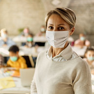 Lehrerin mit Maske vor der Klasse
