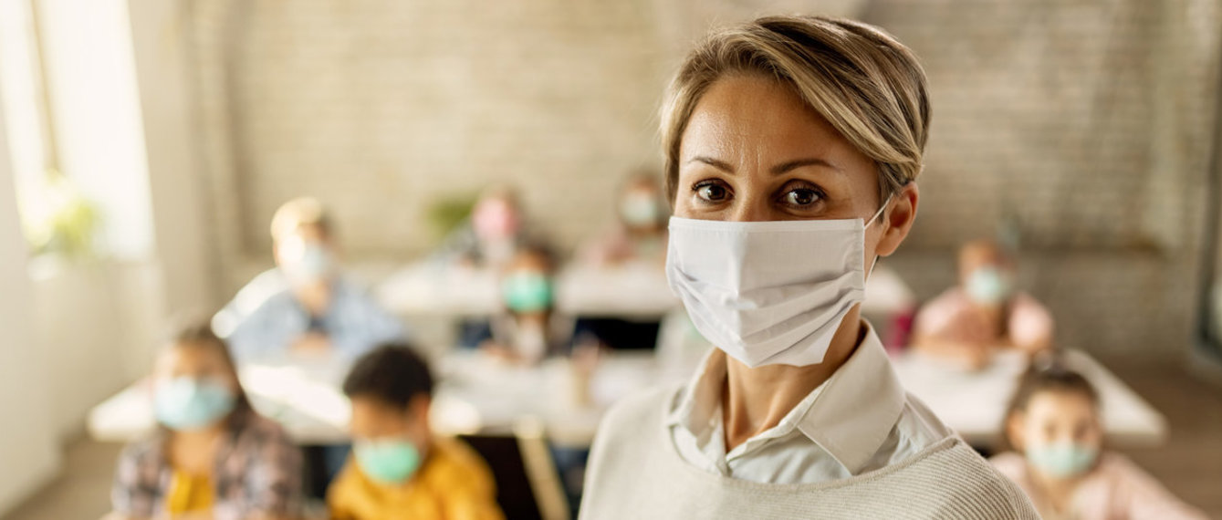 Lehrerin mit Maske vor der Klasse