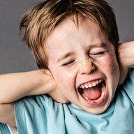 Kind hält sich die Ohren zu