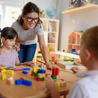 Kindergärtnerin und Kinder spielen