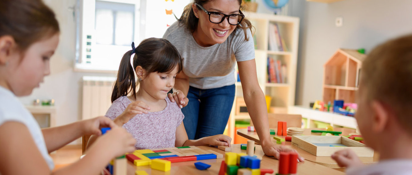 Kindergärtnerin und Kinder spielen