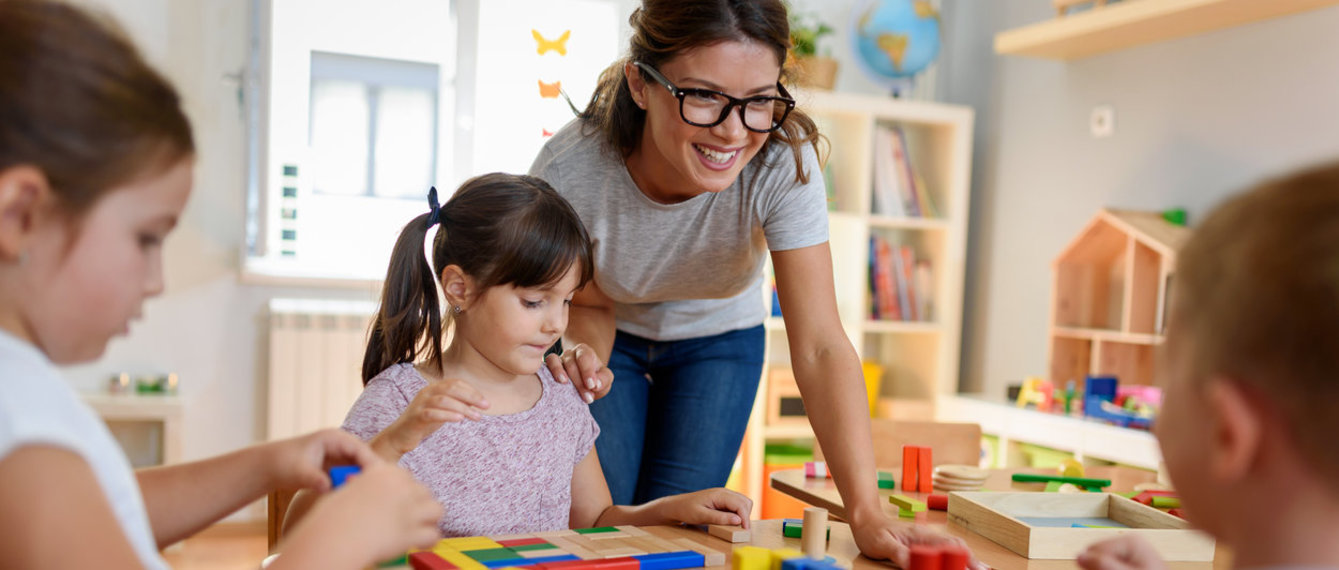 Kindergärtnerin und Kinder spielen