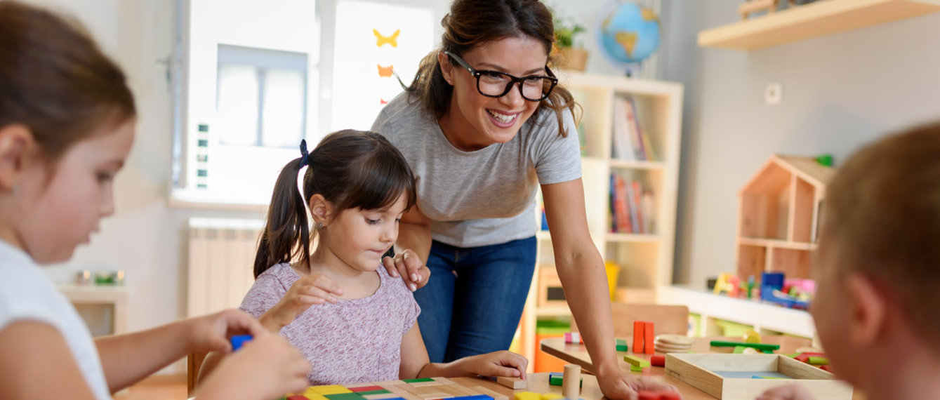 Kindergärtnerin und Kinder spielen