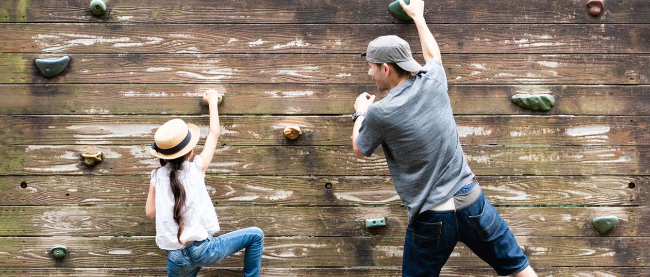 Mann klettert mit Kind auf Kletterwand