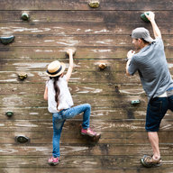 Mann klettert mit Kind auf Kletterwand