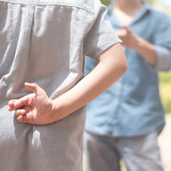  Lüge weibliche Kinderhändlerhand, die die Finger hinten mit Vater vorne kreuzt.