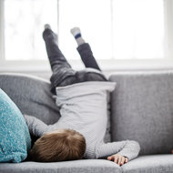 Frustrationstoleranz stärken © iStock Kind liegt demotiviert auf Couch