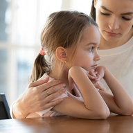 Frau umarmt besorgt Tochter beim Gespräch
