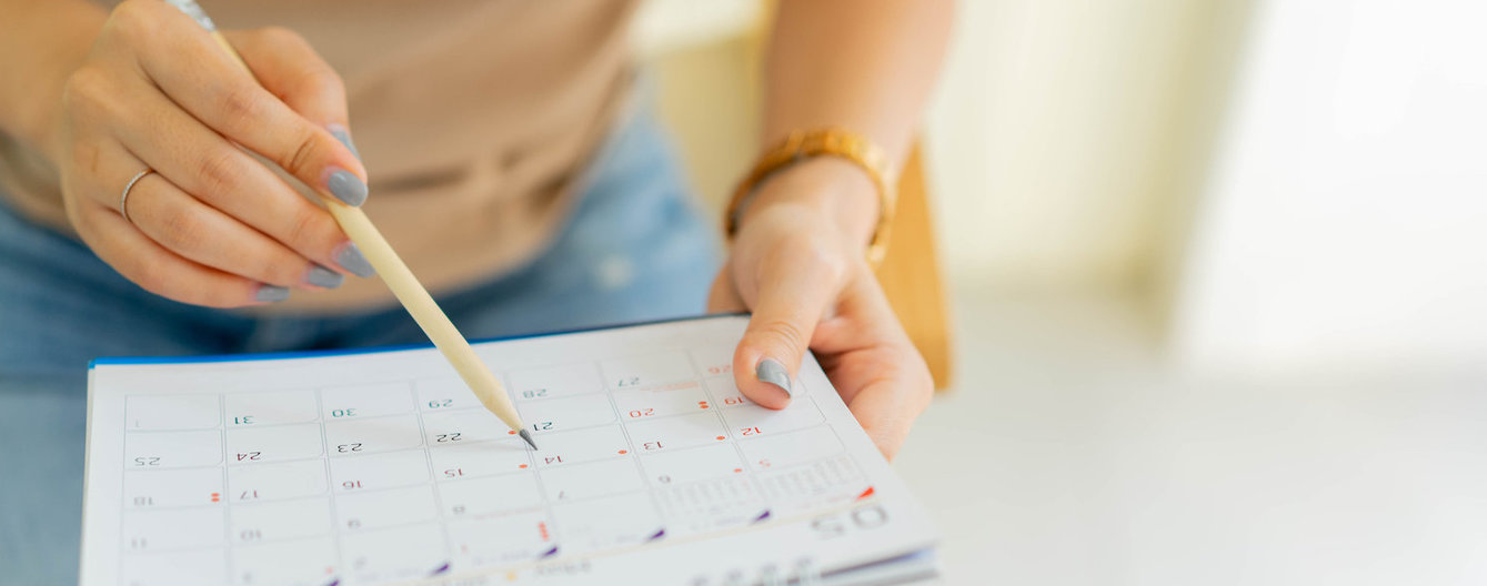 Frauenhand mit Bleistift checkt Kalender