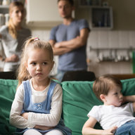 zwei Kinder sitzen unzufrieden auf der Couch