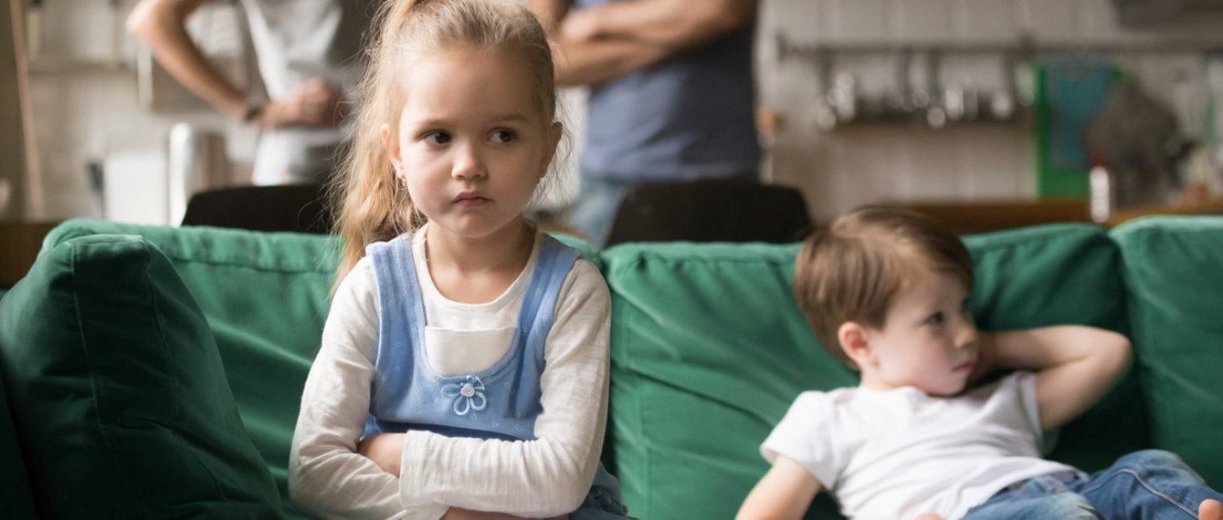 zwei Kinder sitzen unzufrieden auf der Couch