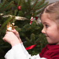 Mädchen betrachtet Engelsfigur am Christbaum