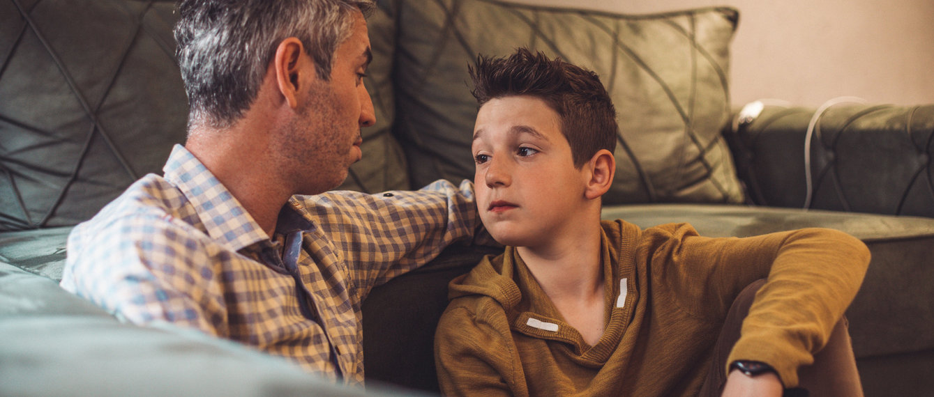 Vater und Sohn sitzen vor Sofa