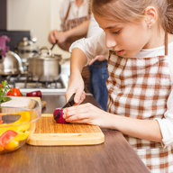 Kleines Mädchen schneidet Zwiebel auf dem Küchentresen.