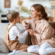 Glückliche Mutter spielt mit Sohn auf dem Sofa