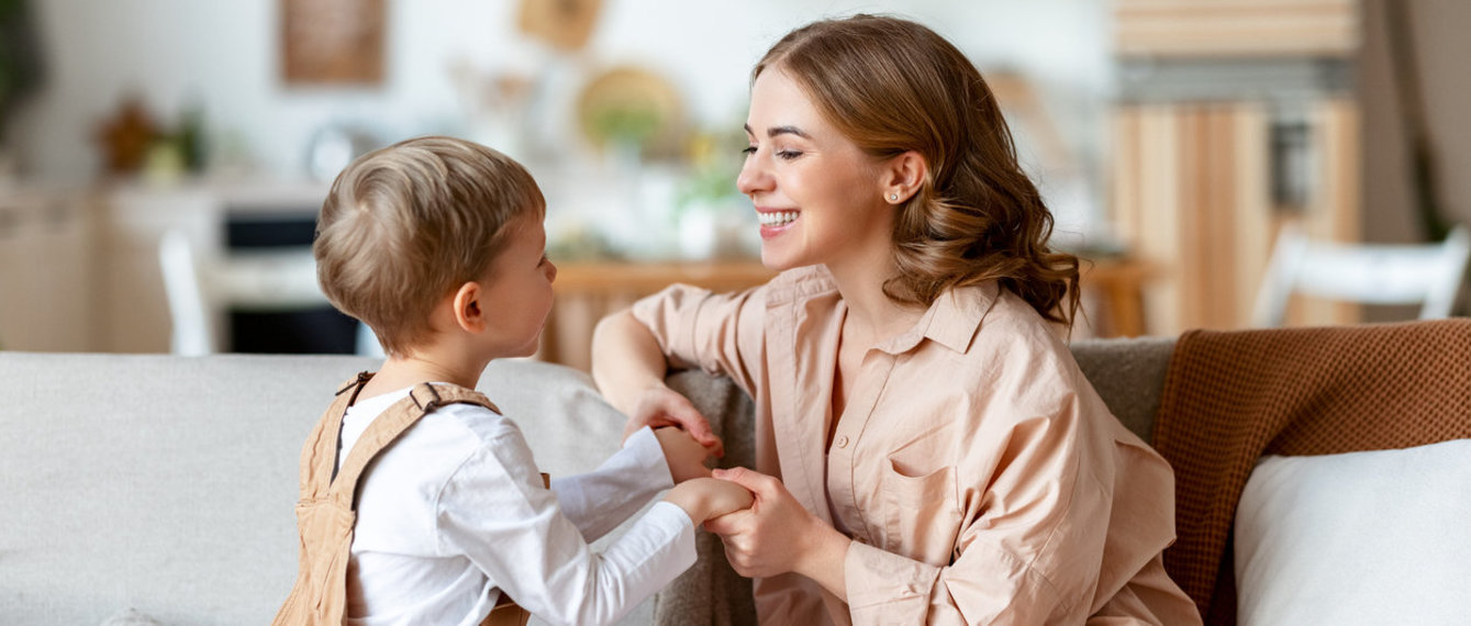 Glückliche Mutter spielt mit Sohn auf dem Sofa