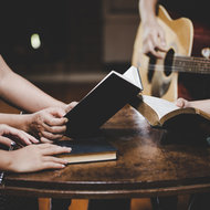 Gitarre spielen im Kirchenraum, Hände mit Liederbüchern