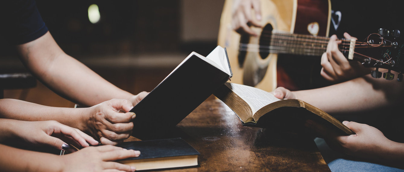 Gitarre spielen im Kirchenraum, Hände mit Liederbüchern