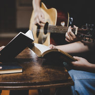 Gitarre spielen im Kirchenraum, Hände mit Liederbüchern