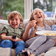 Warum Ausnahmen gut für's Familienleben sind - iStock © iStock Drei Kinder sitzen vorm Fernseher und essen Popcorn