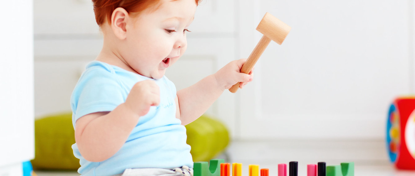 Baby sitzt am Boden und spielt Hammerspiel