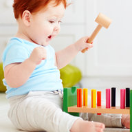 Baby sitzt am Boden und spielt Hammerspiel