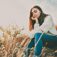 Frau sitzt auf Wiese und denkt nach