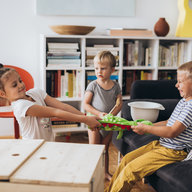 drei kleine kinder streiten um ein stofftier