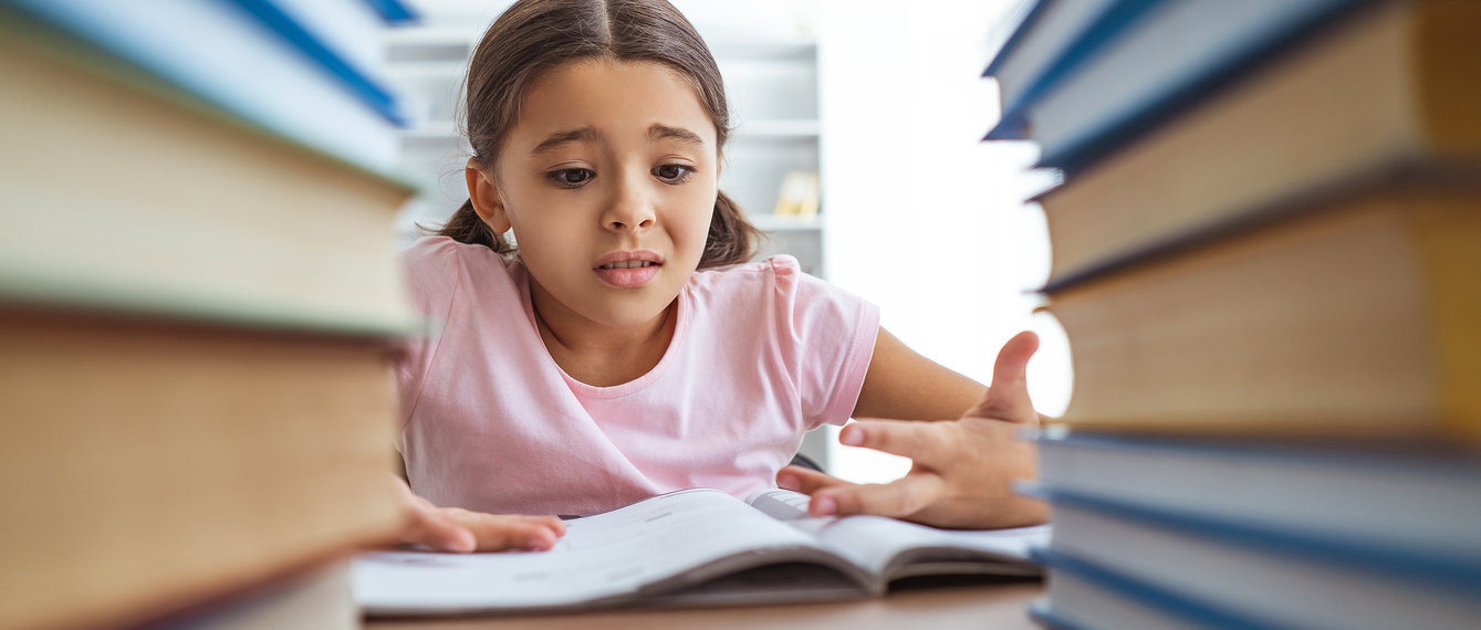 verzweifeltes mädchen sitzt hinter hohem bücherturm