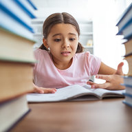 verzweifeltes mädchen sitzt hinter hohem bücherturm