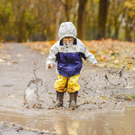 Kind hüpft in Matschpfütze