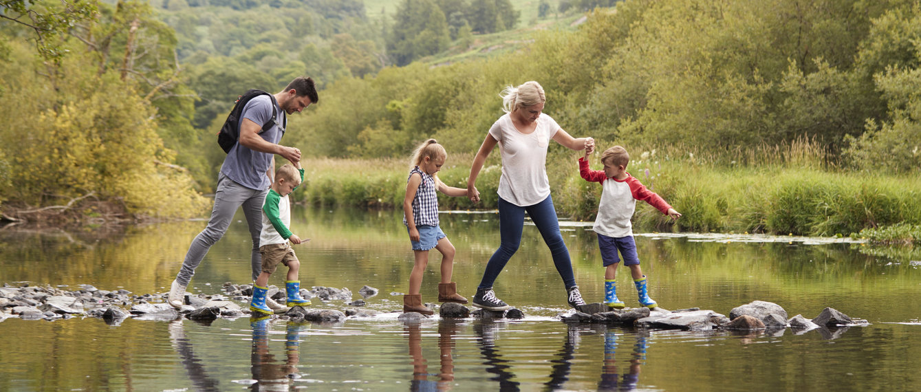 Eltern mit drei Kindern überqueren einen See