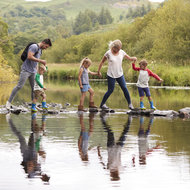 Eltern mit drei Kindern überqueren einen See