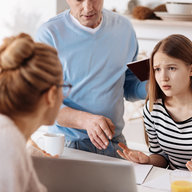 Teenager diskutiert mit Eltern am Küchentisch