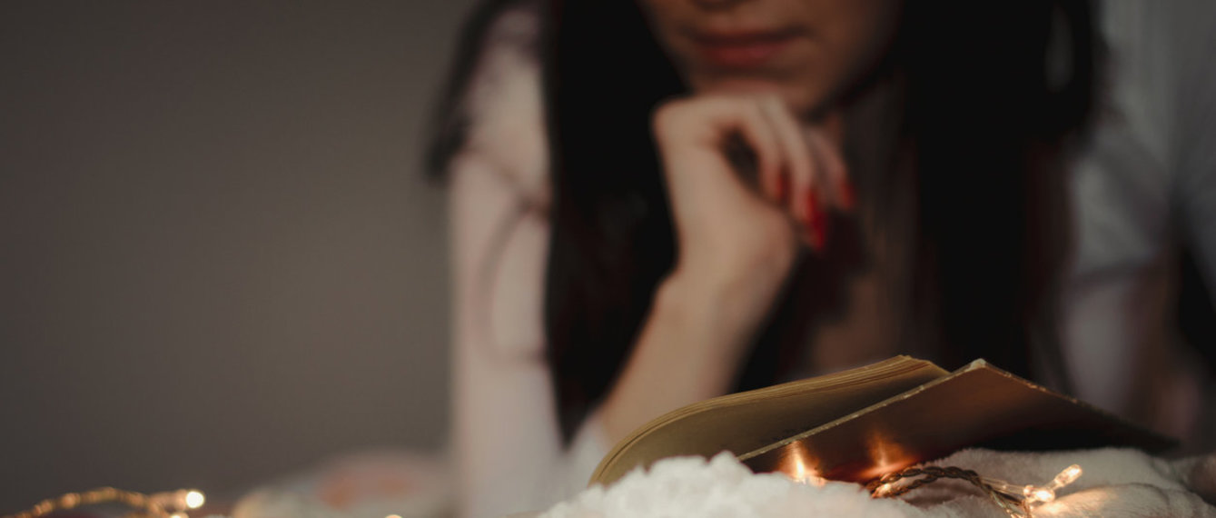 Frau liest bei Lichterkette entspannt ein Buch