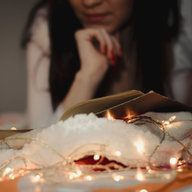 Frau liest bei Lichterkette entspannt ein Buch