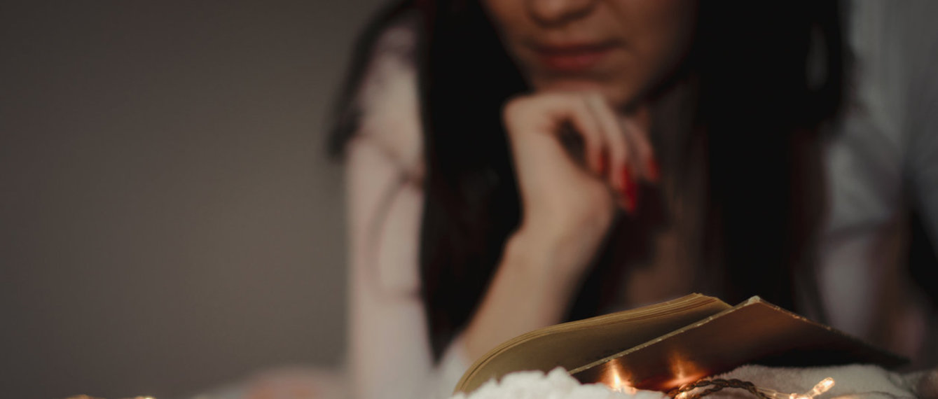 Frau liest bei Lichterkette entspannt ein Buch