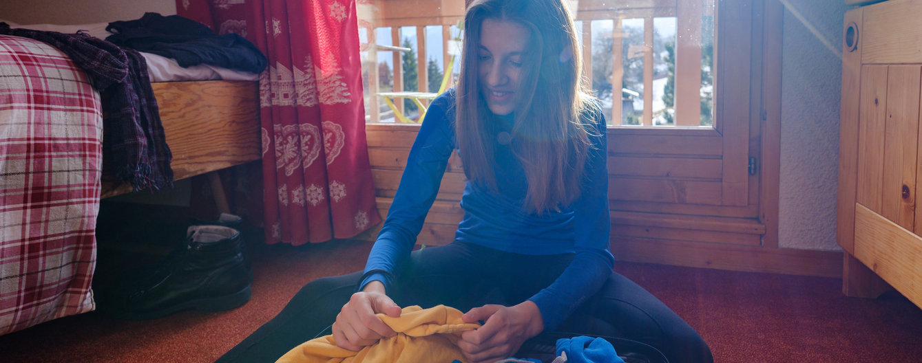 Verreisen mit Kindern © iStock Frau packt Skigewand in Koffer