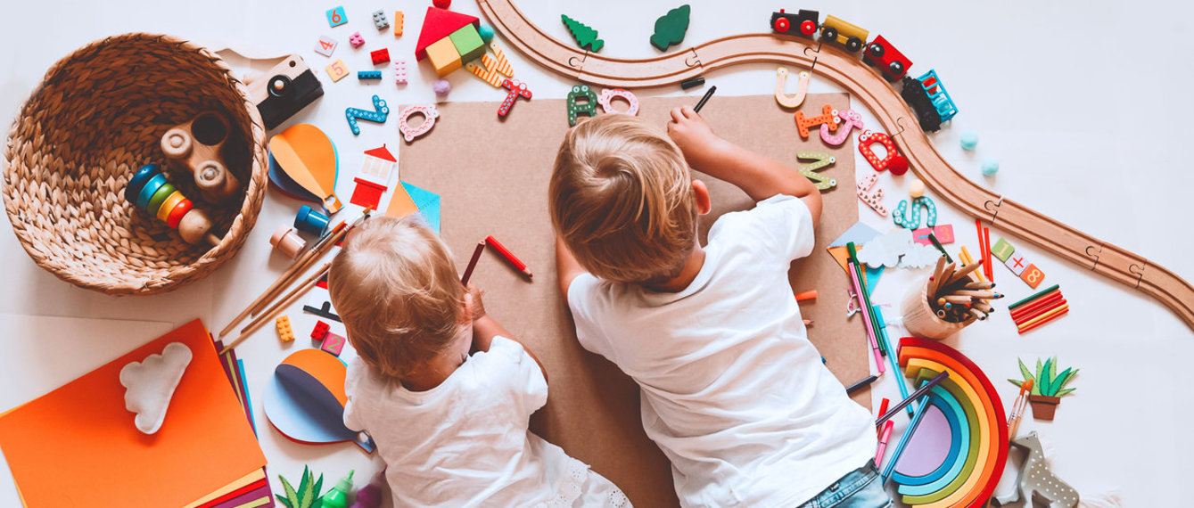 Kinder liegen am Boden, spielen und malen
