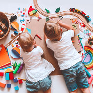 Kinder liegen am Boden, spielen und malen