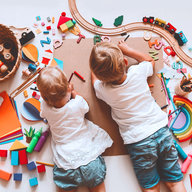 Kinder liegen am Boden, spielen und malen