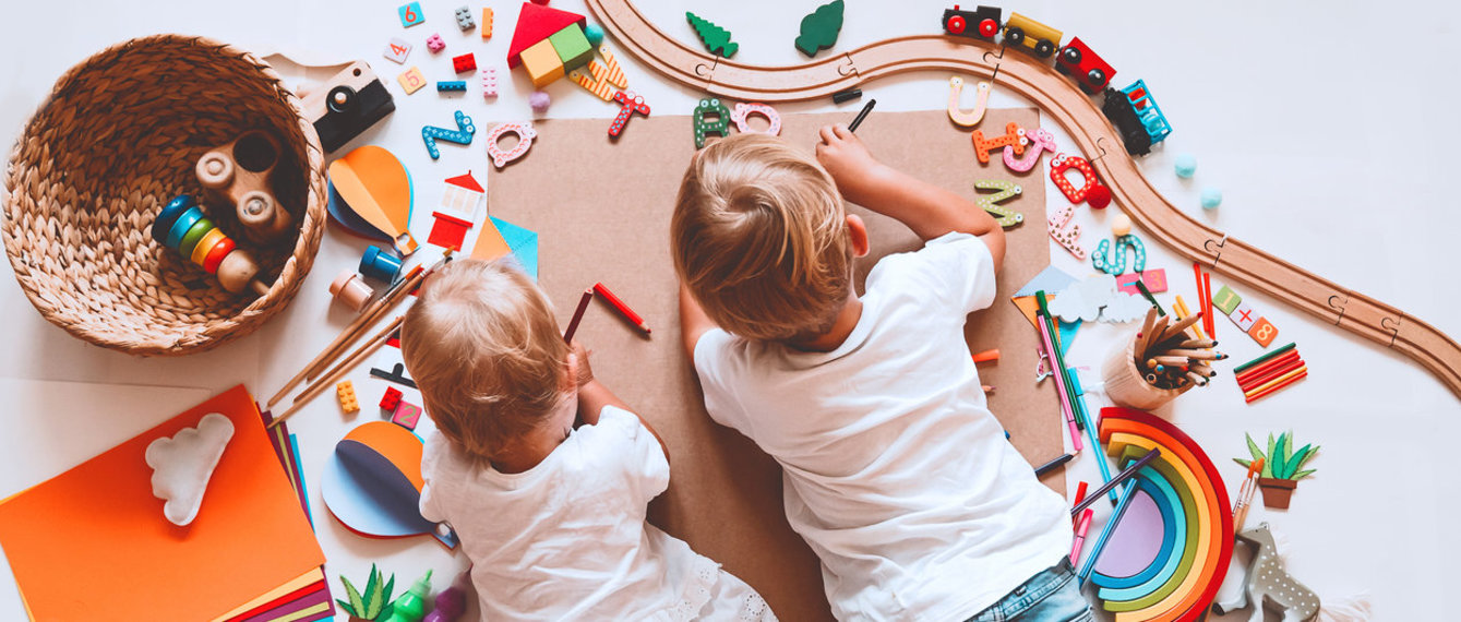 Kinder liegen am Boden, spielen und malen
