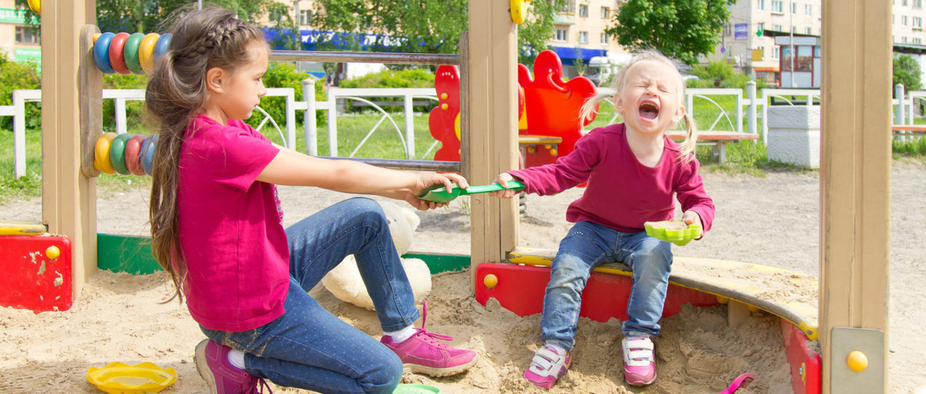 Konflikt auf dem Spielplatz. Zwei Schwestern Streit um ein Spielzeug im Sandkasten. Kleine Schwester Weinen alle Kehle – Stockfoto