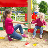 Konflikt auf dem Spielplatz. Zwei Schwestern Streit um ein Spielzeug im Sandkasten. Kleine Schwester Weinen alle Kehle – Stockfoto
