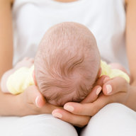 Mutter hält Neugeborenes im Schoß