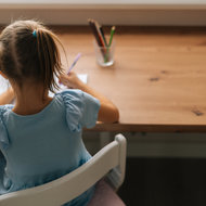 Mädchen sitzt am Schreibtisch und macht Hausübung